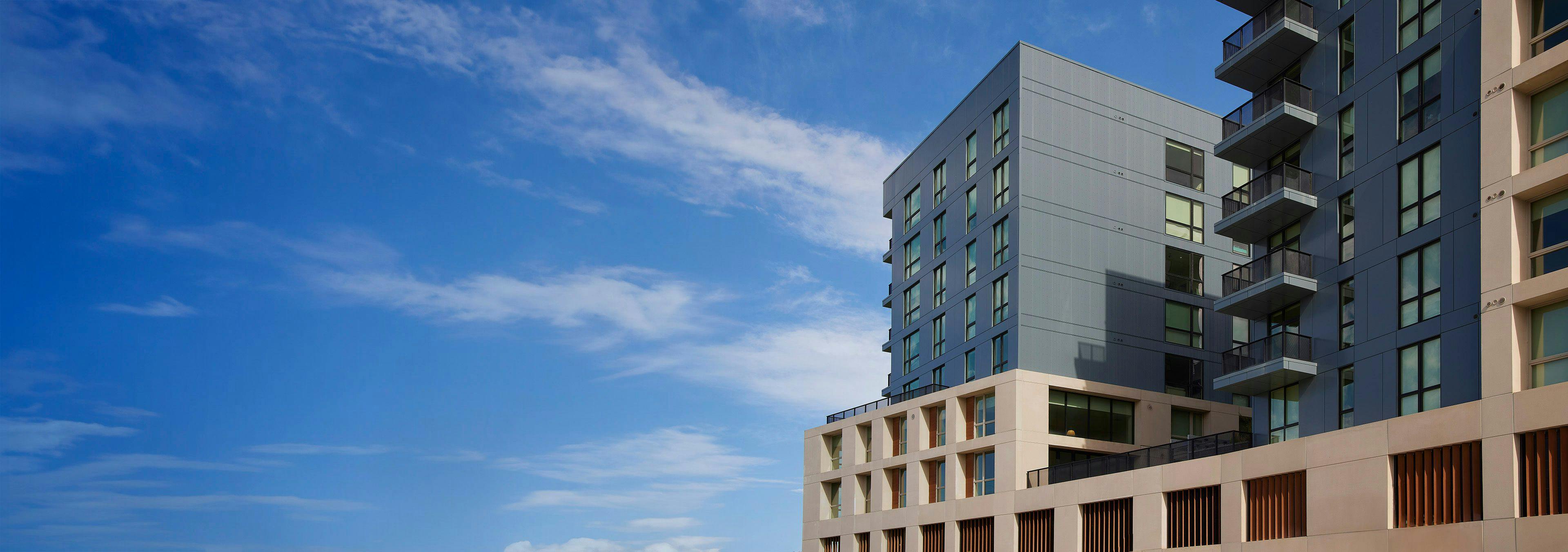 Smart apartment building against a blue sky with wispy clouds.